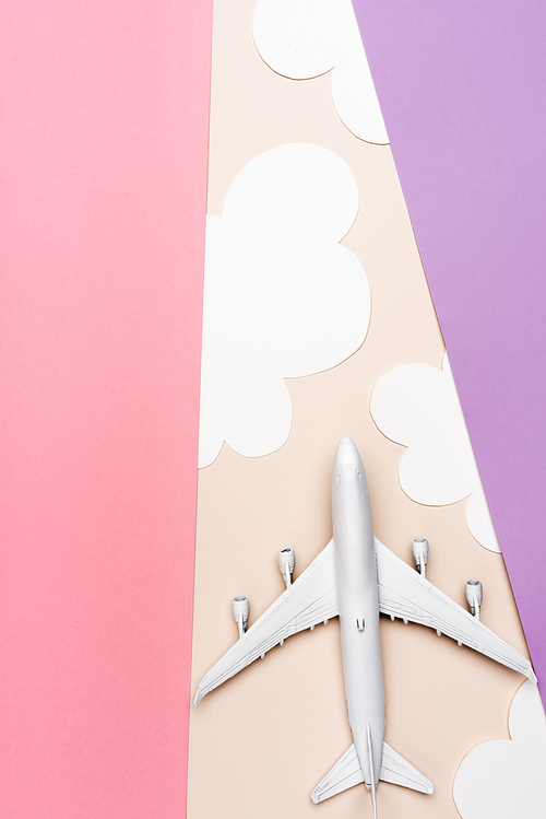 top view of white plane model on colorful background with clouds
