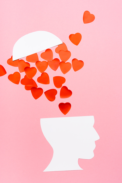 top view of paper human head and heart on pink background