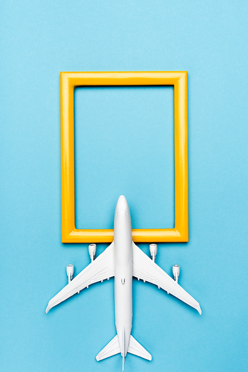 top view of white plane model and empty frame on blue background