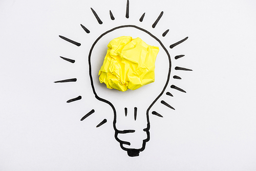 top view of light bulb with crumpled paper on white background