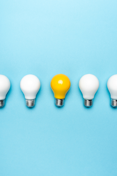 top view of white and yellow light bulbs on blue background