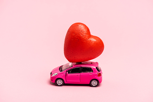 toy car and red heart on pink background