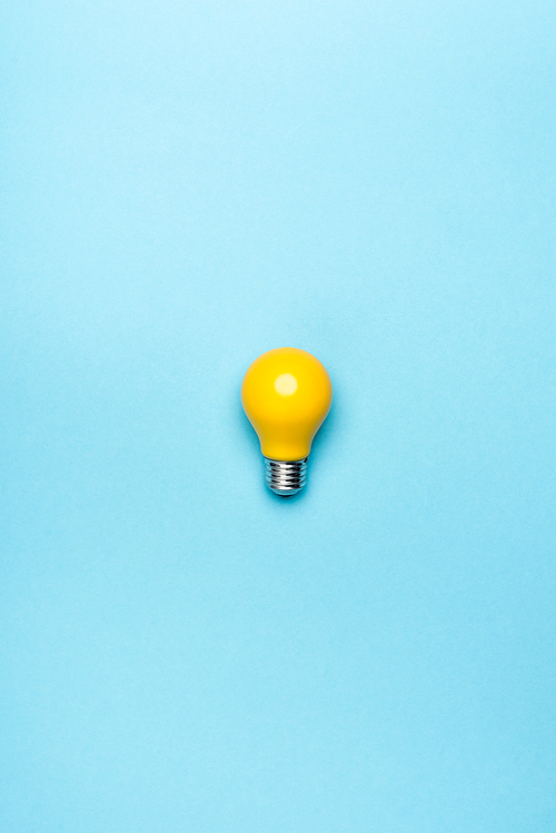 top view yellow light bulb on blue background
