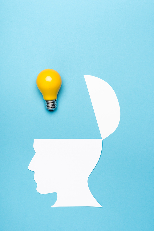 top view yellow light bulb and paper human head on blue background