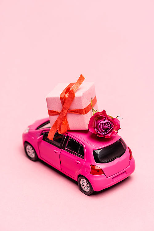 toy car and gift box with rose on pink background