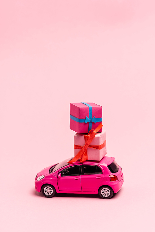 toy car and gift boxes on pink background