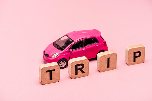 car and word trip on cubes on pink background