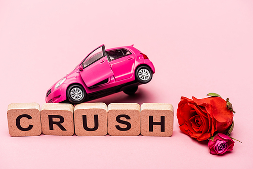 roses, toy car and word crush on cubes on pink background