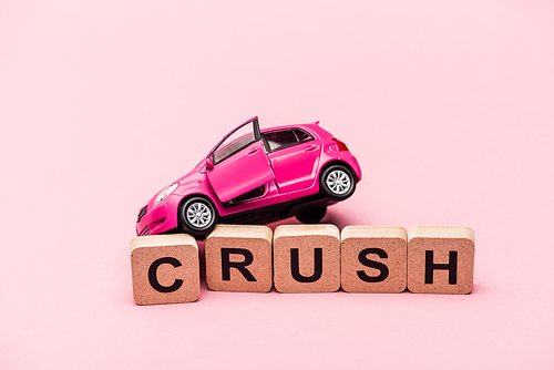 toy car and word crush on cubes on pink background
