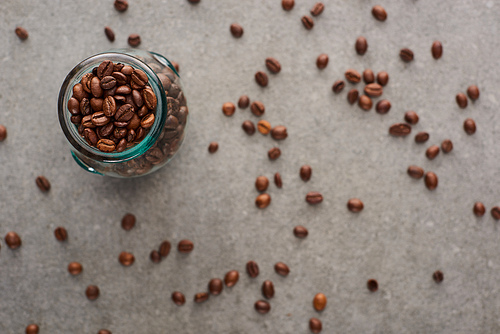 selective focus of coffee grains in glass jar on grey background