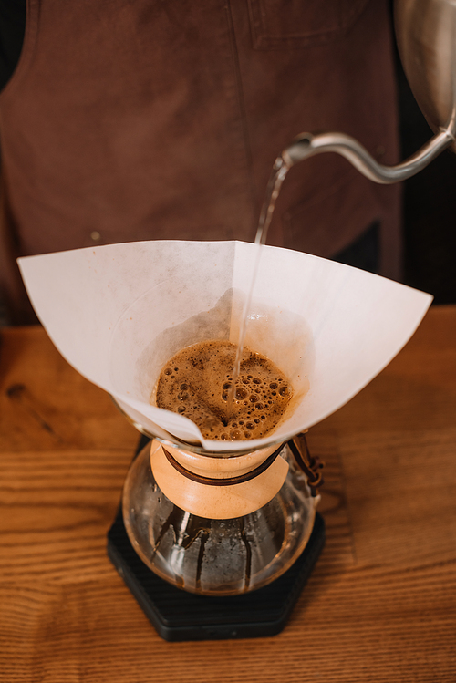 partial view of barista preparing pour-over coffee using Chemex Coffeemaker