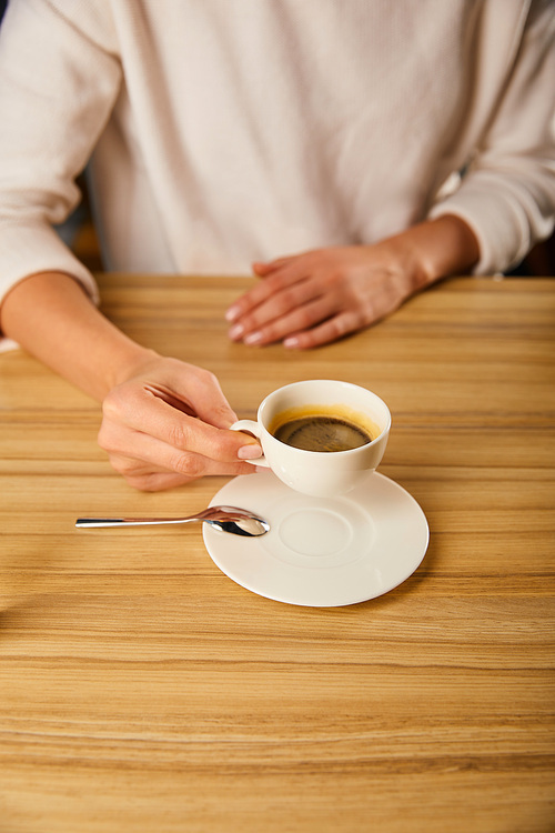 cropped view of woman holding cup with hot coffee in cafe