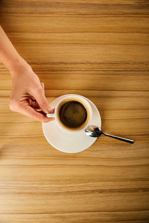 top view of woman holding cup of coffee in cafe