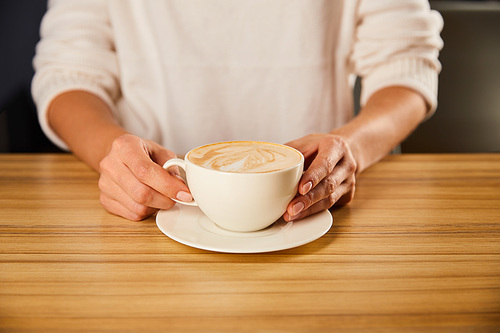 cropped view of woman holding cup of cappuccino