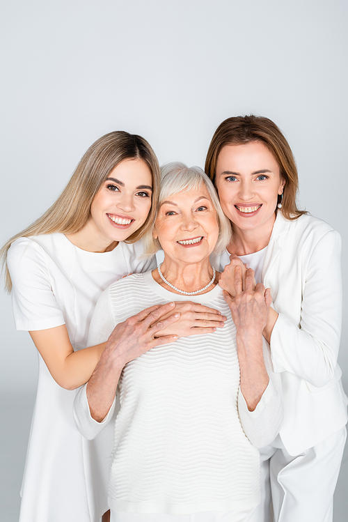 three generation of happy women smiling while  isolated on grey