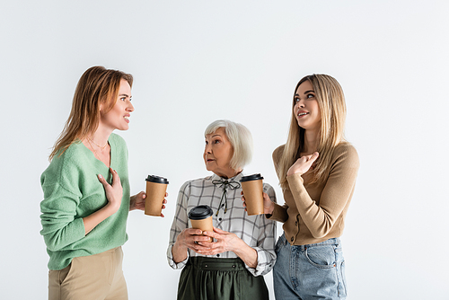 three generation of women holding paper cups and arguing isolated on white