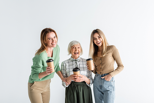 three generation of cheerful women holding paper cups isolated on white