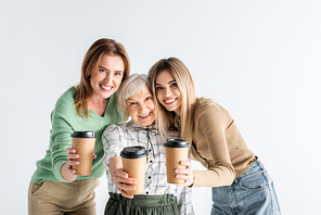 three generation of happy women holding paper cups in outstretched hands isolated on white