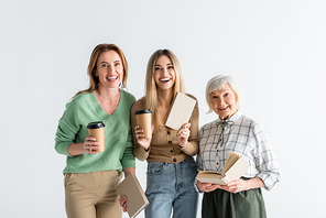 three generation of cheerful women holding paper cups and books isolated on white