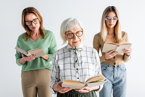 three generation of women in glasses reading books isolated on white