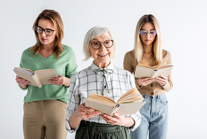 three generation of happy women in glasses reading books isolated on white