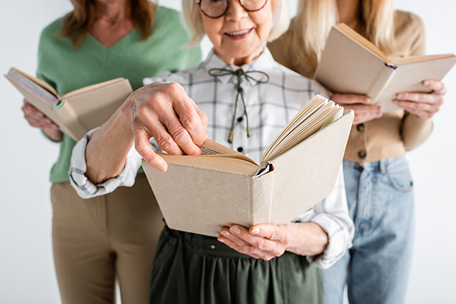 cropped view of three generation of women in glasses reading books isolated on white