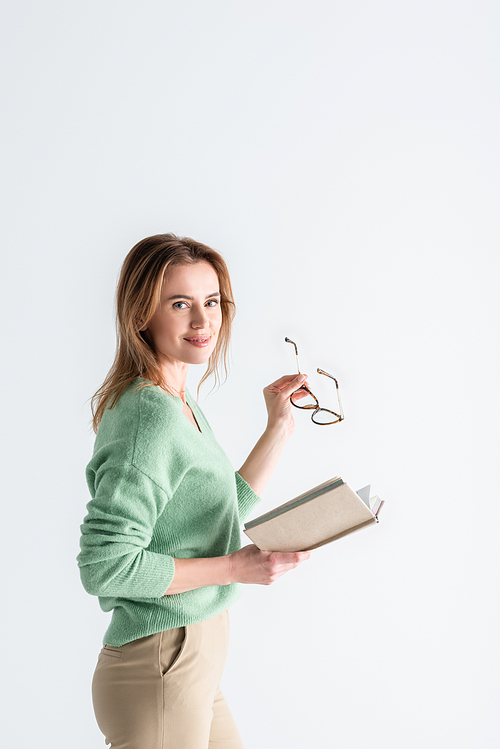 cheerful woman holding glasses and book isolated on white