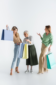 full length of three generation of happy women holding shopping bags on white