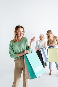 happy woman with shopping bags near daughter and senior mother on blurred background