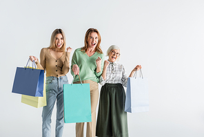 three generation of amazed women holding shopping bags isolated on white
