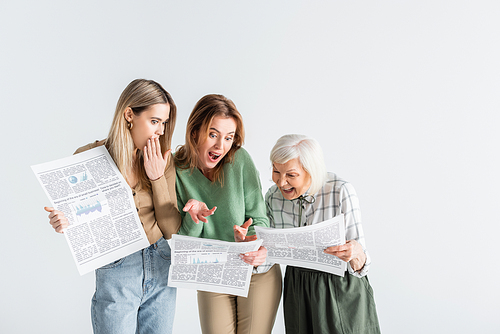 three generation of surprised women reading newspapers isolated on white