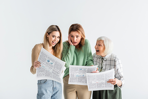 three generation of astonished women reading newspapers isolated on white