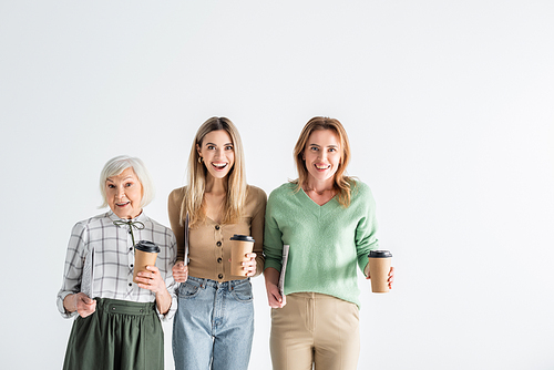three generation of excited women holding newspapers and paper cups isolated on white
