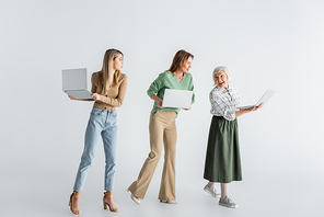 full length of three generation of women with laptops on white
