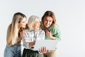 three generation of happy women looking at laptop isolated on white