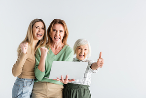 three generation of happy women , showing thumb up and holding laptop isolated on white