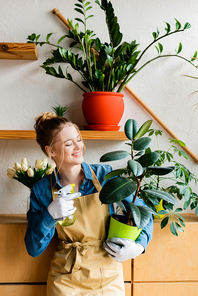 happy woman holding spray bottle and green plant