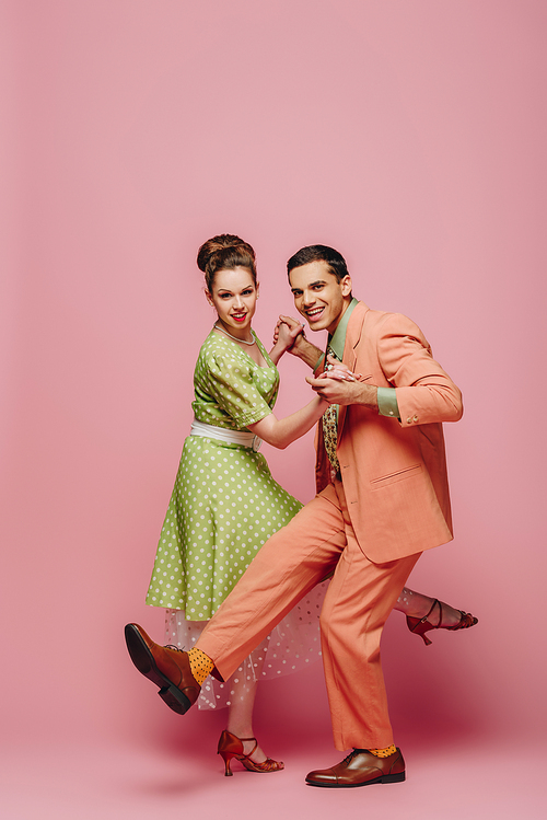young dancers holding hands while dancing boogie-woogie on pink background