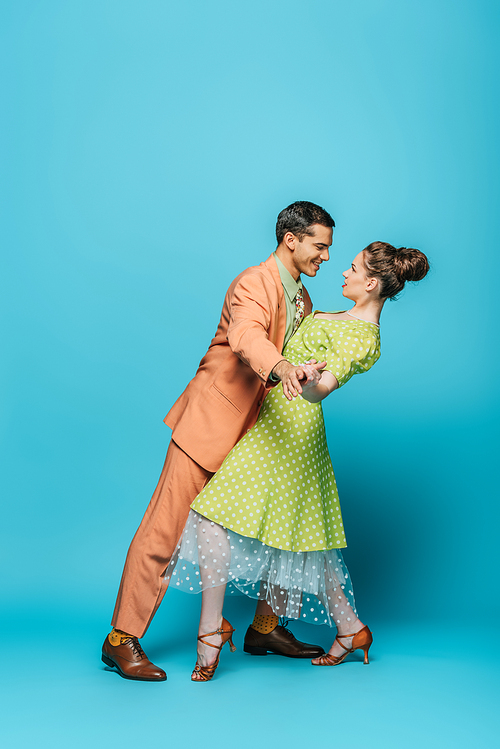 side view of stylish dancers dancing boogie-woogie on blue background