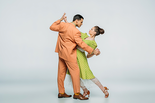 stylish dancers looking at each other while dancing boogie-woogie on grey background
