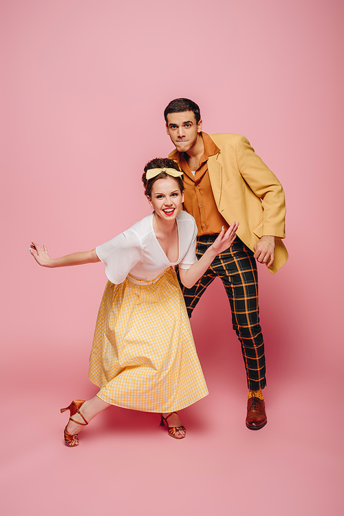 cheerful couple  while dancing boogie-woogie on pink background