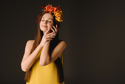 beautiful and brunette woman with closed eyes in wreath isolated on black