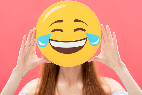 front view of redhead girl holding laughing smiley isolated on pink