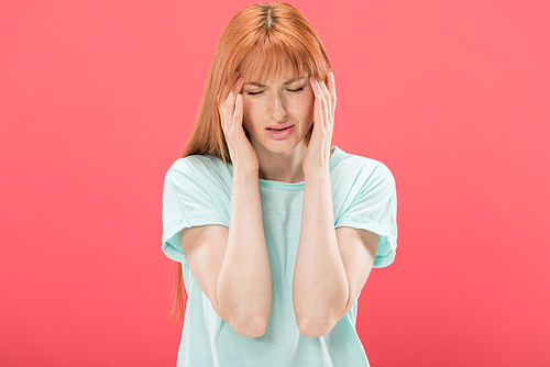 front view of young redhead woman in t-shirt with headache touching head isolated on pink