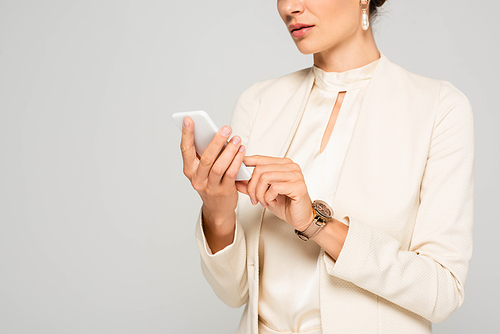 cropped view of businesswoman in white suit using smartphone, isolated on grey