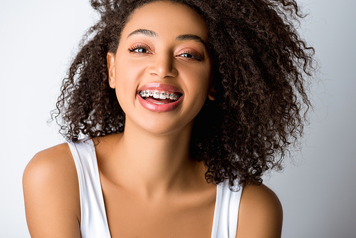 laughing african american girl with dental braces, isolated on grey