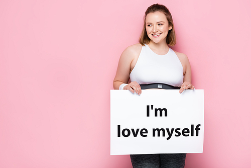 smiling overweight girl holding placard with i love myself inscription on pink