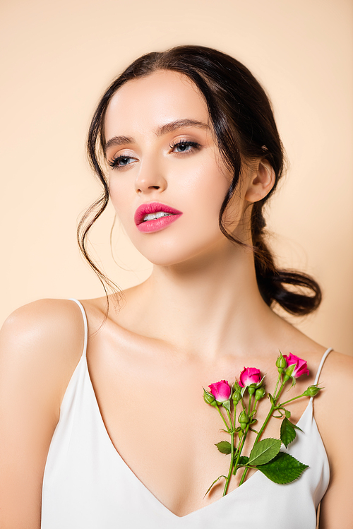 sensual young woman looking away near flowers isolated on pink