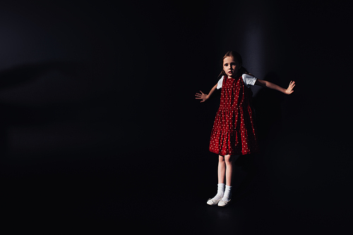 frightened, lonely child  while standing on black background