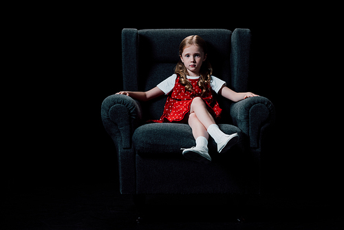 lonely child sitting in armchair and  isolated on black